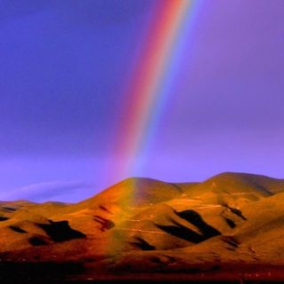 The start of a rainbow over a desert, after sunset.
