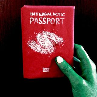 An alien (green) hand, holding a intergalactic passport showing a galaxy spiral on it's front cover.